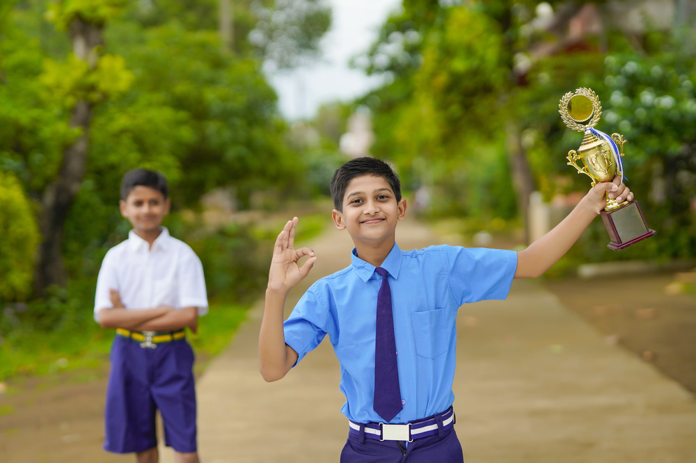 schoolboy raising his trophy as a winner in school for 100% attendance